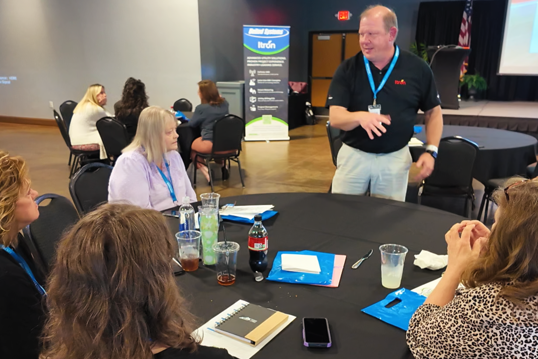 A group of people sitting a semi-circle at a table during the United Systems 2026 User Conference, looking at Matt Steinkamp. He's a Senior Account Manager.